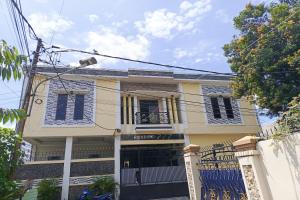 duży biały dom z niebieskimi okiennicami w obiekcie OYO 93650 Pondok Baruga 777 w Kendari