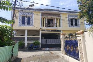 una casa amarilla con una puerta azul delante de ella en OYO 93650 Pondok Baruga 777, en Kendari