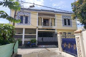 a house with a gate and a blue fence at Hotel O Pondok Baruga 777 Near Sarewo Musik Studio Kendari in Kendari