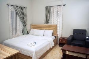 een slaapkamer met een bed en een stoel bij JIKSONODO HOTEL AND SUITE in Nsukka