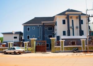 een blauw-wit huis met een auto ervoor bij JIKSONODO HOTEL AND SUITE in Nsukka