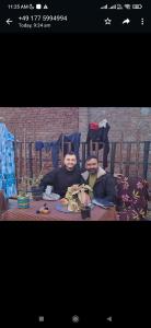 dos personas sentadas en una mesa con comida en Shiva guest House (hoche poche cafe ) en Agra
