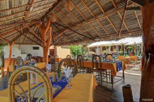 a dining room with tables and chairs and a wooden ceiling at Fleurs d'Ylang in Nosy Be