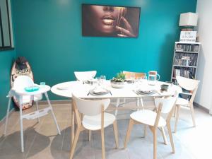 tavolo e sedie bianchi in una stanza con parete blu di Maison BELIZO, familiale ,calme et reposante. a Vernet