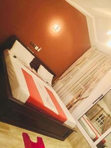 - une petite chambre avec un lit et un fauteuil rouge dans l'établissement La belle au bois dormant, à Abomey-Calavi