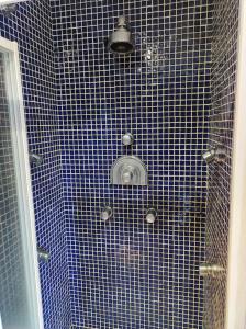 - une douche carrelée de bleu avec une porte en verre dans l'établissement Chalet con piscina climatizada., 
