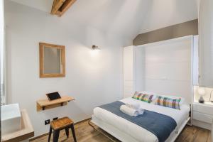 Habitación blanca con cama y espejo en Le Petit Chalet - Maison 2 chambres avec terrasse en Rennes