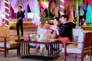 a man and a woman sitting at a table at a party at Temple Da Nang Resort in Danang