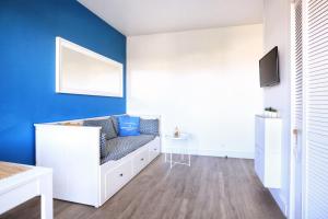 a living room with a white couch and a blue wall at Terrasse de Chimay - Charmant apt dans résidence front de mer in Barneville-Carteret