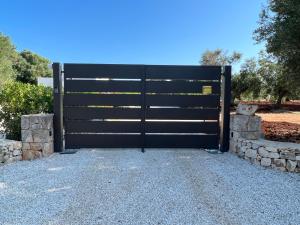eine schwarze Garagentür mit einer Steinmauer in der Unterkunft Le Lamie di Ostuni in San Michele Salentino