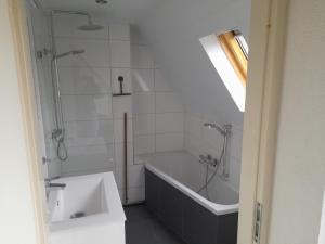ein Badezimmer mit einer Badewanne und einem Waschbecken in der Unterkunft t'Hoog Holt in Gramsbergen