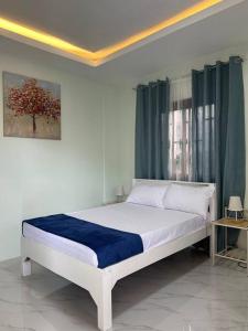 a bedroom with a white bed with a blue blanket at Faith Street Airbnb in Plaridel