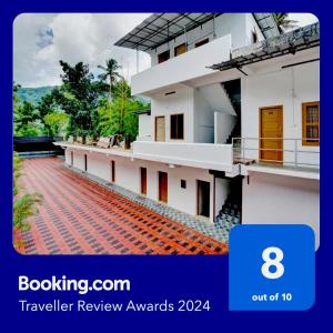 a white building with a red brick walkway at Flagship Thottunkal Building Thodupuzha in Neriyamangalam