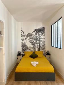een slaapkamer met een geel bed en handdoeken bij Les Remparts in Fougères