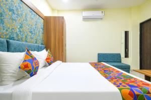 a hotel room with a bed and two blue chairs at FabHotel Grand Giriraj in Indore