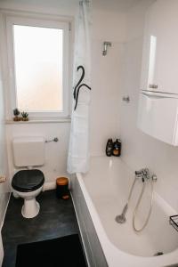 a bathroom with a toilet and a tub and a window at Modern & black - City - Netflix - Wifi - 4 Person in Bochum