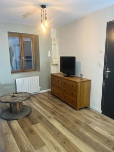 ein Wohnzimmer mit einem TV und einem Holztisch in der Unterkunft Le 24 carat appartement 3 pièces neuf in Beaurepaire