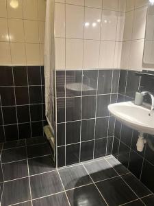 a black and white tiled bathroom with a sink at Le 24 carat appartement 3 pièces neuf in Beaurepaire