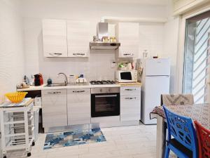 a kitchen with white cabinets and a white refrigerator at Villino due palme in Palumbo