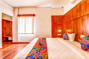 a bedroom with a large bed with a wooden wall at FabHotel V Suites Bangalore East Railway Station in Bangalore