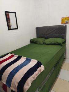 um quarto com uma cama com lençóis verdes e um espelho em QQ HOMESTAY em Takengon