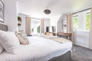 a white bedroom with a large bed and windows at Abbey Villa - Stylish House - Central with Parking in St Andrews