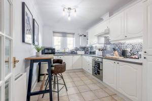 a kitchen with white cabinets and a table in it at Abbey Villa - No 6 in St. Andrews +9 photos
