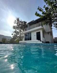 a house with a swimming pool in front of a house at Aum Villa Pet Friendly in Karjat