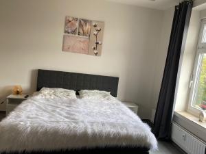 1 dormitorio con 1 cama con edredón blanco y ventana en Ferienwohnung PIER 1 in Cuxhaven, en Cuxhaven