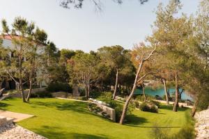 a garden with trees and a lake in the background at Villa Contessa - Top 200 ultra luxury world villas in Mali Lošinj