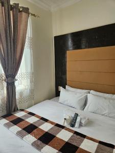 1 dormitorio con 1 cama con mando a distancia en DBright Lodge en Pretoria