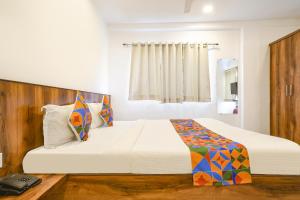 um quarto com uma grande cama branca e uma janela em FabExpress The King Palace em Indore