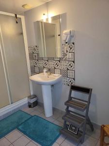 a bathroom with a sink and a mirror and a chair at Auberge de la vallée de la douve in L'Etang-Bertrand