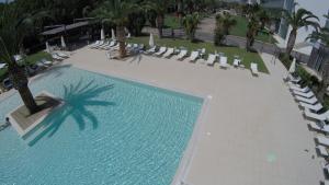 an overhead view of a swimming pool with chairs and palm trees at Eureka Palace Hotel Spa Resort in Cassibile
