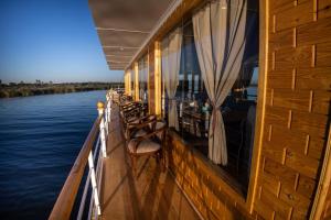 盧克索的住宿－Dahabiya Akhnaton Every Monday from Esna to Aswan for 4 Nights，一个带桌椅的船的阳台