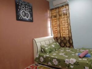 a bedroom with a bed with a green comforter and a window at Homestay Ainul in Pendang