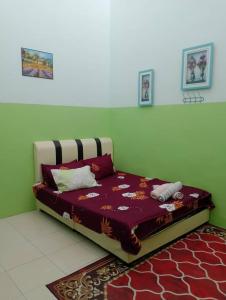 Bett in einem Zimmer mit grüner Wand in der Unterkunft Homestay Ainul in Pendang