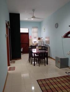 Homestay Ainul في Pendang: غرفة مع طاولة وكراسي ومطبخ