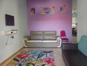 a living room with a couch and a pink wall at Ainul 74 Homestay in Pendang