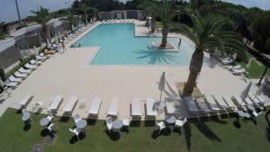 an overhead view of a swimming pool with chairs and palm trees at Eureka Palace Hotel Spa Resort in Cassibile