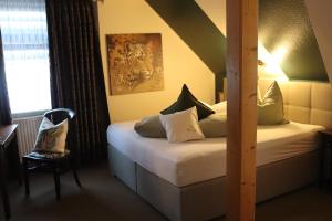 a bedroom with two beds and a chair and a window at Hotel Kropper Busch Garni in Kropp