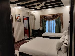 イスラマバードにあるCapri Executiveのベッド2台と窓が備わるホテルルームです。