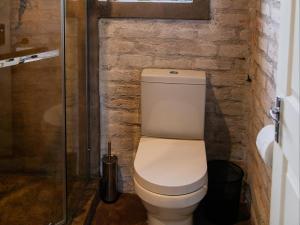 a white toilet in a bathroom with a brick wall at Klipplaatsdrift Safari Lodge in Hofmeyr