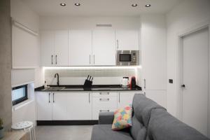a kitchen with white cabinets and a gray couch at Ponteloft - Recuncho in Pontevedra