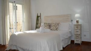 a white bedroom with a white bed and a window at Mahonia Palacio Congresos Parking Concertado in Granada