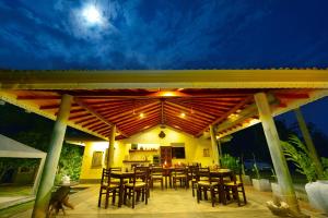 a patio with wooden tables and chairs at night at The Horizon Hill Top Villa in Unawatuna