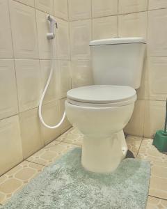 a white toilet in a bathroom with a hose at Goodtimewithfar House in Moshi