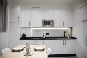 a white kitchen with a table and a microwave at Ponteloft - Xeitoso in Pontevedra