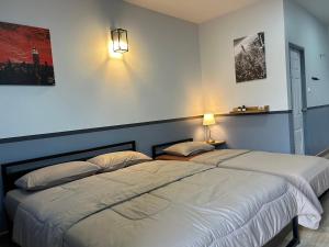 two beds in a bedroom with two lamps on the wall at บ้านสุขซอย5 in Kanchanaburi City