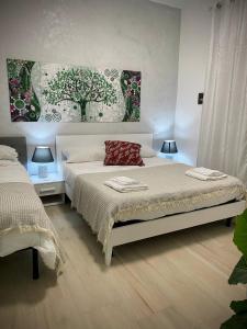a bedroom with two beds and two lamps and a painting at Central Apartments in Crotone